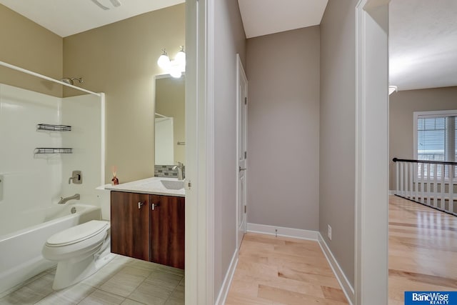 bathroom with baseboards, tub / shower combination, toilet, and vanity