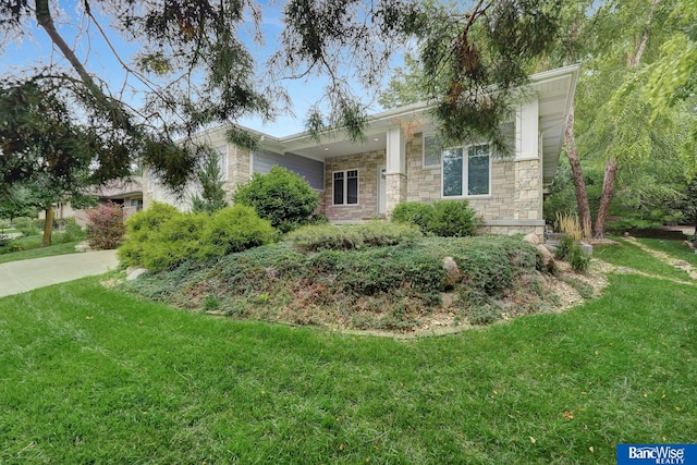 view of front of property featuring stone siding, concrete driveway, and a front yard