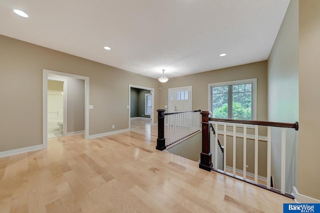 hall featuring light wood finished floors, baseboards, an upstairs landing, and recessed lighting