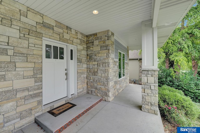 doorway to property with stone siding and covered porch