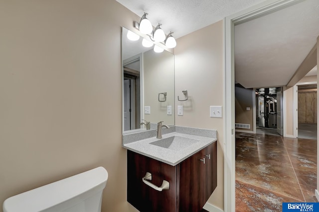 bathroom featuring concrete flooring, vanity, toilet, a textured ceiling, and visible vents