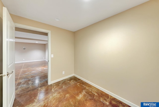 spare room featuring concrete flooring and baseboards