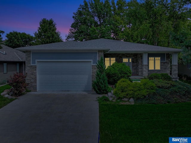 view of front of house with stone siding, roof with shingles, concrete driveway, a front lawn, and a garage