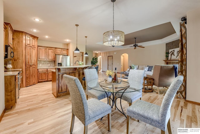 dining room featuring ceiling fan, light wood-style flooring, arched walkways, baseboards, and recessed lighting