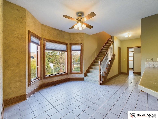 interior space with stairs, a ceiling fan, baseboards, and light tile patterned floors