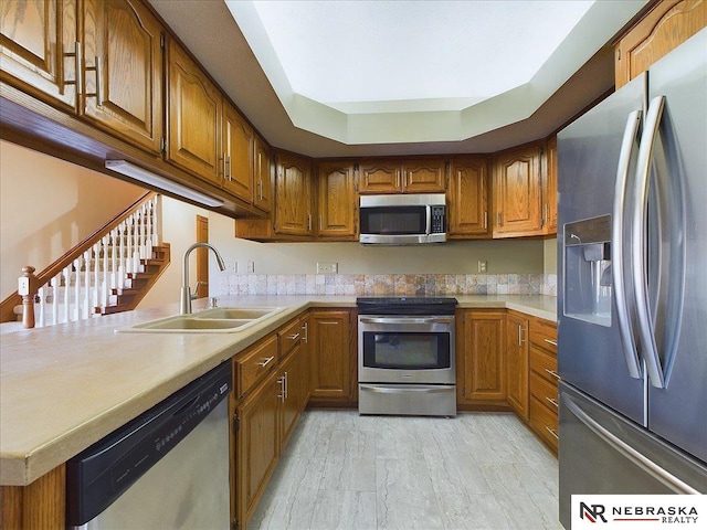 kitchen featuring a sink, light countertops, brown cabinets, and appliances with stainless steel finishes