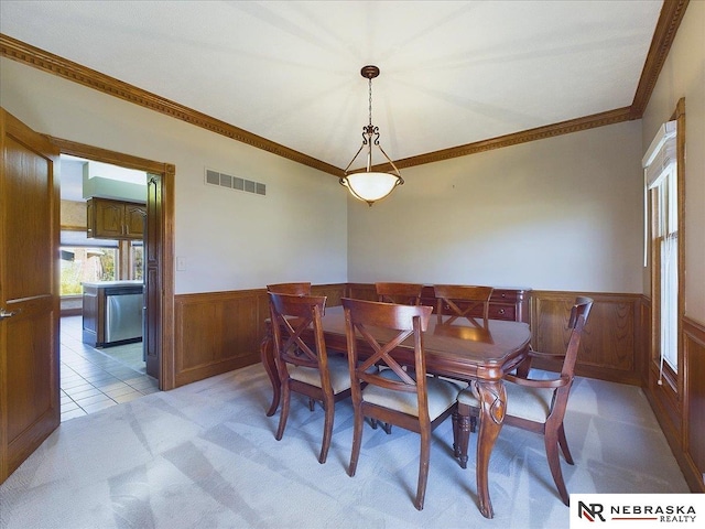 dining room with ornamental molding, a wainscoted wall, light carpet, and visible vents