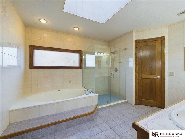 full bathroom featuring tile walls, tile patterned floors, a stall shower, visible vents, and a bath