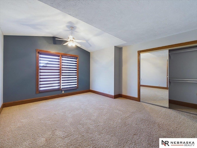 unfurnished bedroom with baseboards, lofted ceiling, carpet flooring, and a textured ceiling