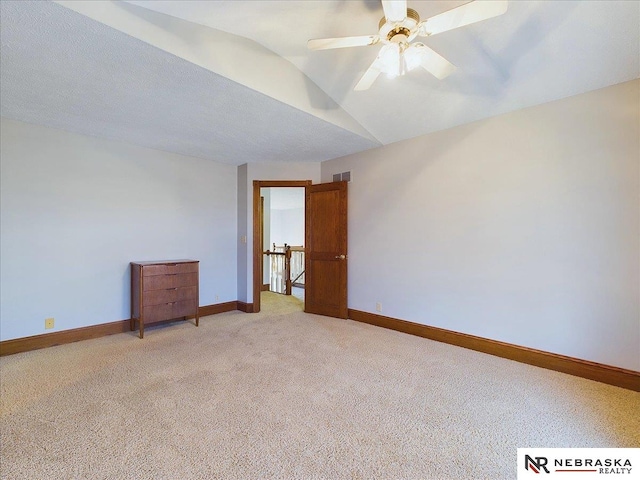 empty room with visible vents, baseboards, a ceiling fan, light carpet, and vaulted ceiling