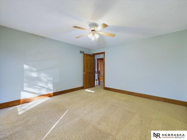 empty room featuring light carpet, baseboards, visible vents, and ceiling fan
