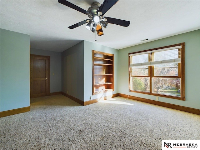 carpeted spare room featuring a ceiling fan, a textured ceiling, baseboards, and visible vents