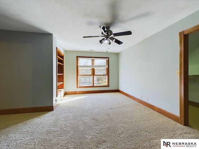 empty room with a ceiling fan, carpet, baseboards, and a textured ceiling