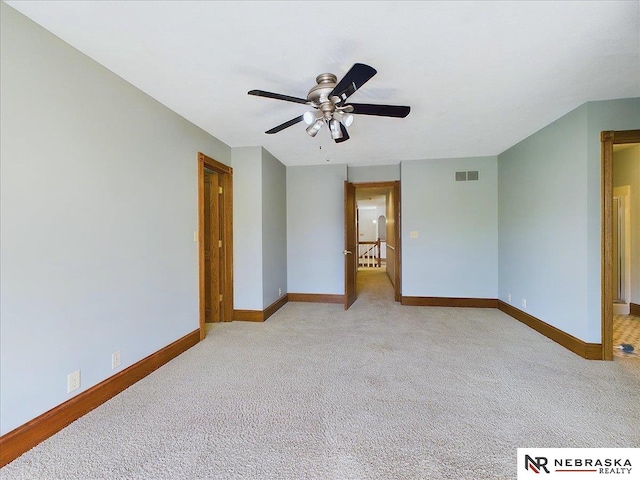carpeted empty room with baseboards, visible vents, and a ceiling fan