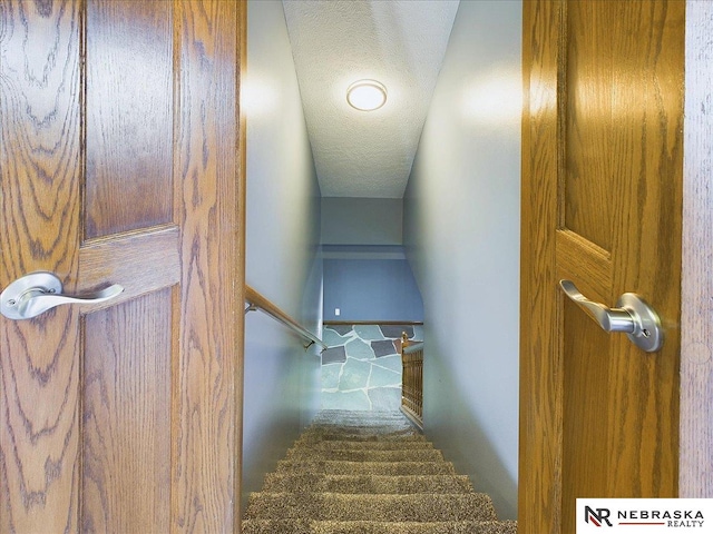 stairs featuring a textured ceiling