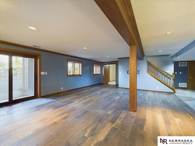 unfurnished living room featuring visible vents, baseboards, stairway, and wood finished floors