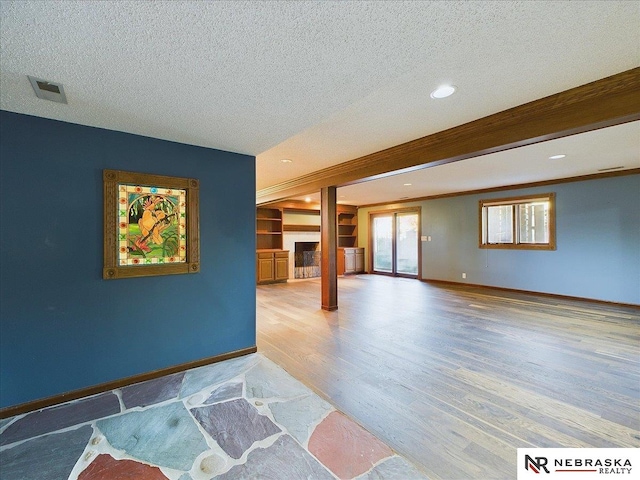 living room with a textured ceiling, visible vents, light wood-style flooring, baseboards, and recessed lighting