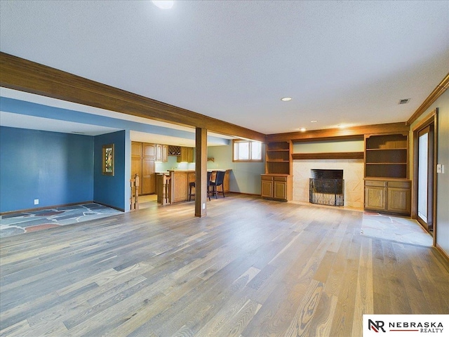 unfurnished living room with visible vents, baseboards, a fireplace, and wood finished floors