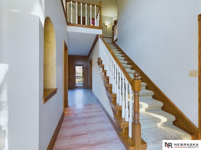 stairway with baseboards, arched walkways, and a towering ceiling