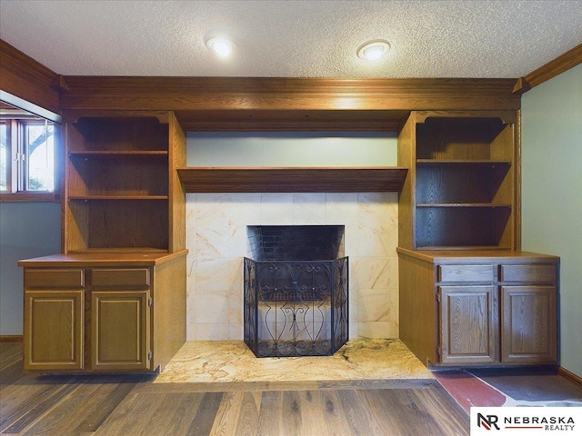 unfurnished living room with a tiled fireplace, dark wood-type flooring, and a textured ceiling