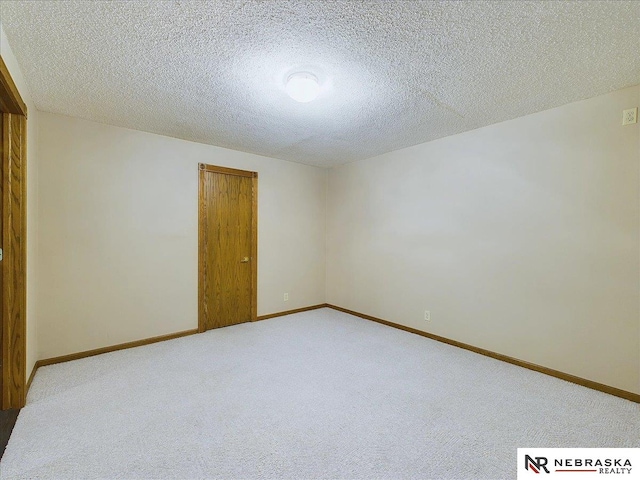 empty room featuring baseboards, light colored carpet, and a textured ceiling
