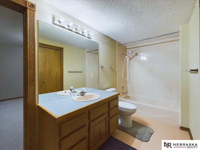 full bath featuring a textured ceiling, toilet, vanity, shower / washtub combination, and tile patterned flooring