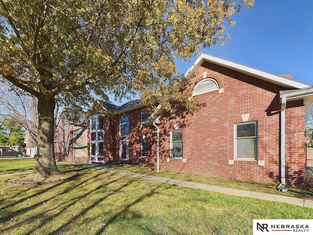 view of property exterior with brick siding and a lawn