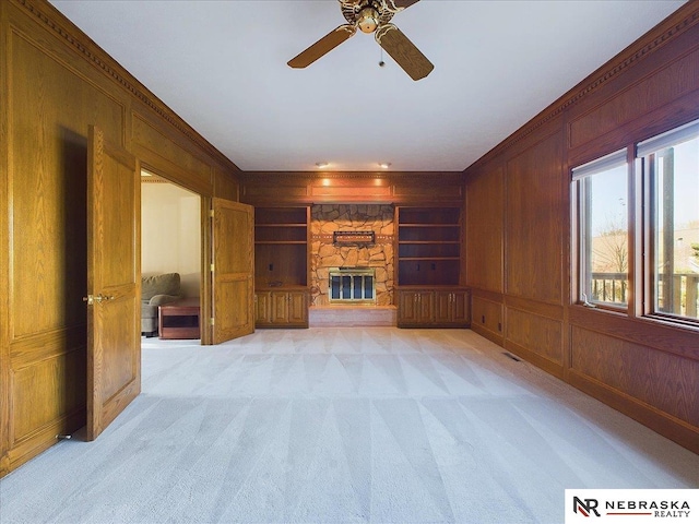 living area with a fireplace, wood walls, light colored carpet, and built in shelves