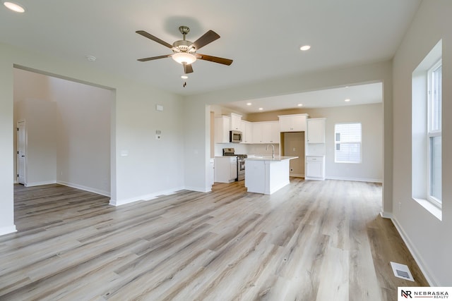 17547 Potter St, Bennington, NE 68007 - unfurnished living room featuring a ceiling fan, baseboards, light wood-style floors, and visible vents