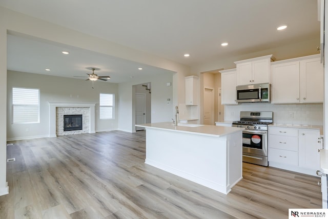 17547 Potter St, Bennington, NE 68007 - kitchen with light countertops, backsplash, a ceiling fan, appliances with stainless steel finishes, and light wood-style floors