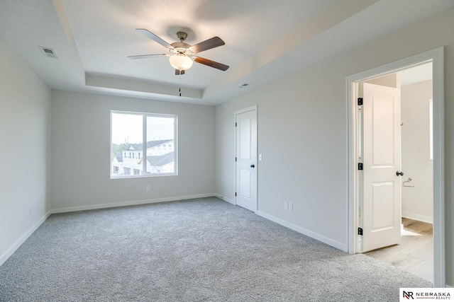 17547 Potter St, Bennington, NE 68007 - unfurnished bedroom with baseboards, a tray ceiling, visible vents, and light colored carpet