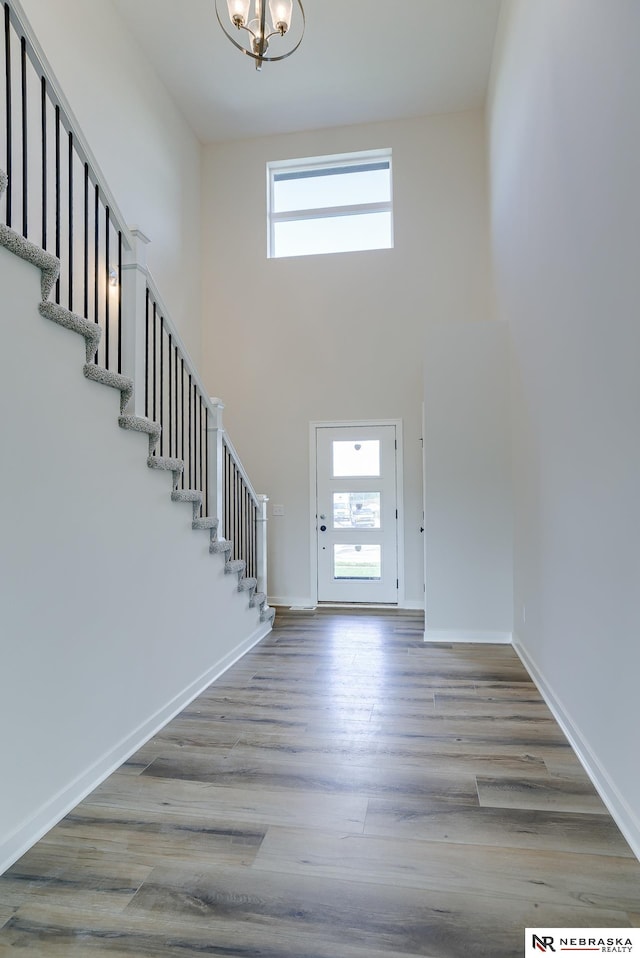 17547 Potter St, Bennington, NE 68007 - foyer featuring stairs, a notable chandelier, a high ceiling, wood finished floors, and baseboards