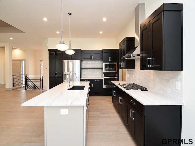 kitchen featuring a kitchen island with sink, dark cabinetry, a sink, and stainless steel appliances