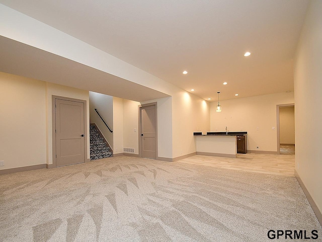 finished below grade area featuring stairs, recessed lighting, wet bar, baseboards, and light carpet