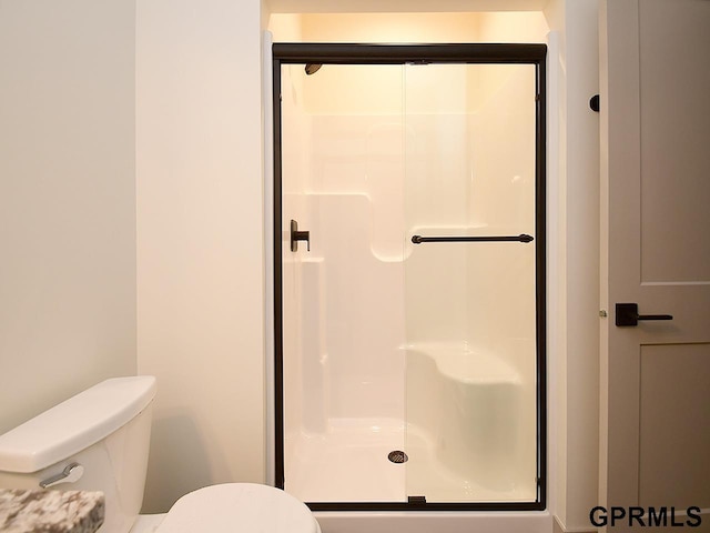 bathroom with toilet and a stall shower