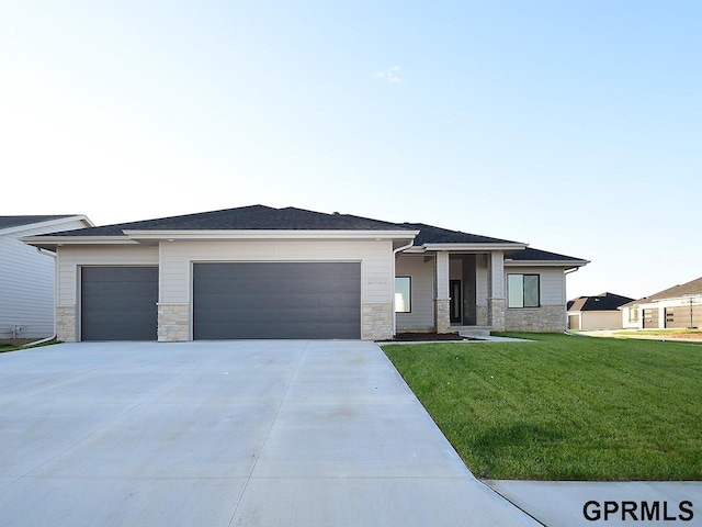 prairie-style home featuring stone siding, an attached garage, a front lawn, and driveway