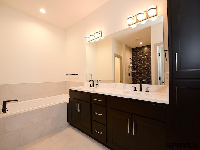 bathroom with double vanity, a tile shower, a sink, and a garden tub