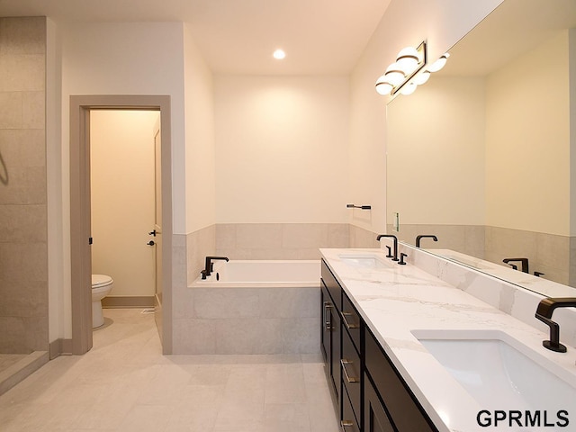 bathroom with double vanity, toilet, a sink, and a garden tub