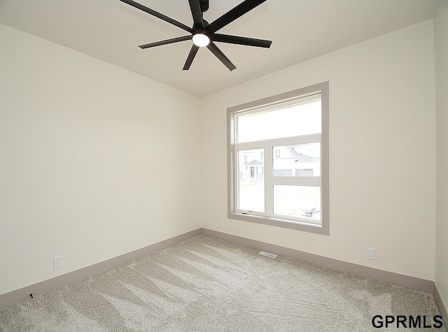spare room featuring carpet floors, baseboards, visible vents, and ceiling fan