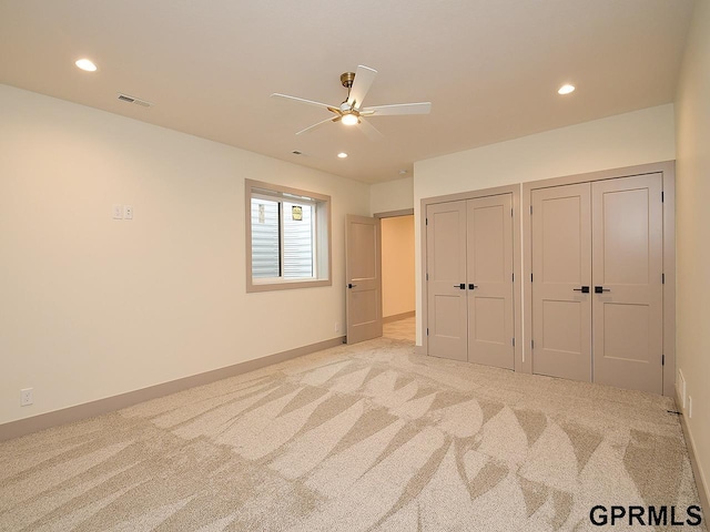 unfurnished bedroom featuring visible vents, two closets, baseboards, recessed lighting, and light carpet