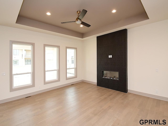 spare room featuring light wood-style flooring, visible vents, a ceiling fan, and a raised ceiling