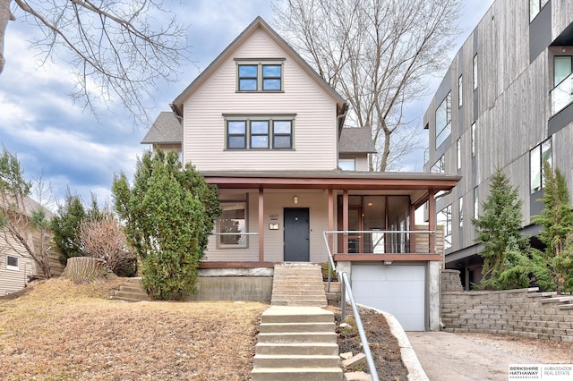 view of front of house with stairs, covered porch, concrete driveway, an attached garage, and a shingled roof