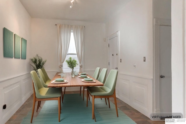 dining area featuring a wainscoted wall, a decorative wall, and wood finished floors