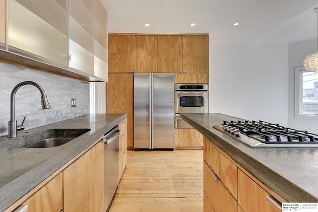 kitchen with light wood-type flooring, stainless steel appliances, decorative backsplash, a sink, and modern cabinets