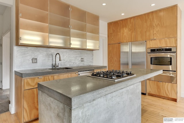 kitchen featuring decorative backsplash, light wood-style flooring, stainless steel appliances, dark countertops, and a sink