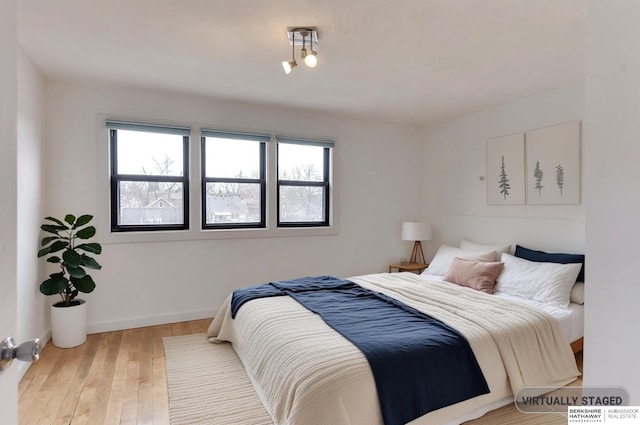 bedroom with baseboards, multiple windows, and wood finished floors