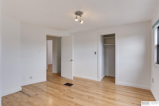 unfurnished bedroom featuring a closet, baseboards, light wood finished floors, and visible vents