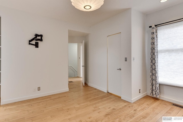 spare room with baseboards, visible vents, and hardwood / wood-style flooring