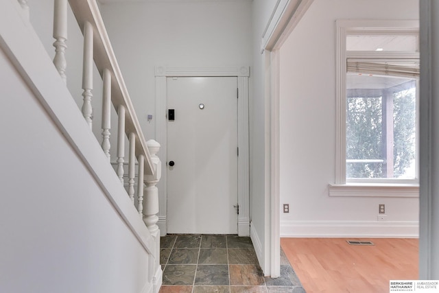 entrance foyer featuring baseboards, visible vents, stairway, and stone finish flooring