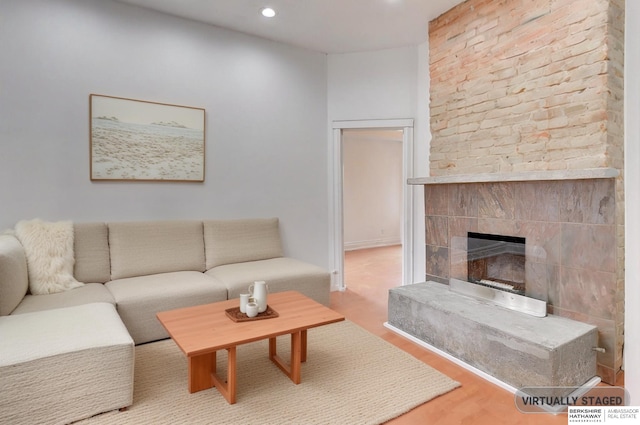 living room with wood finished floors, a tile fireplace, and recessed lighting